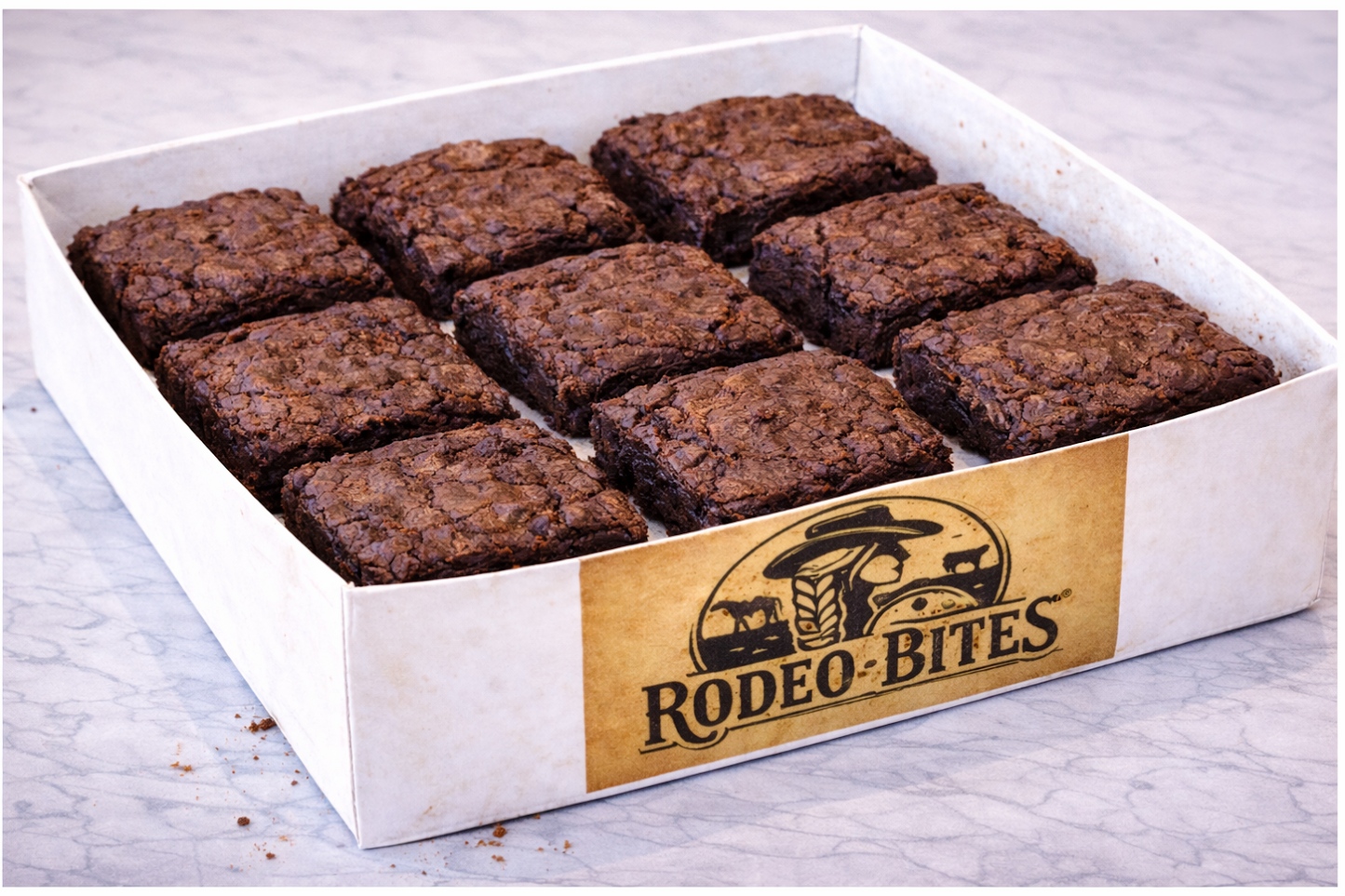 Box of Rodeo Bites brownies in a Rodeo Bites box on a marble surface.