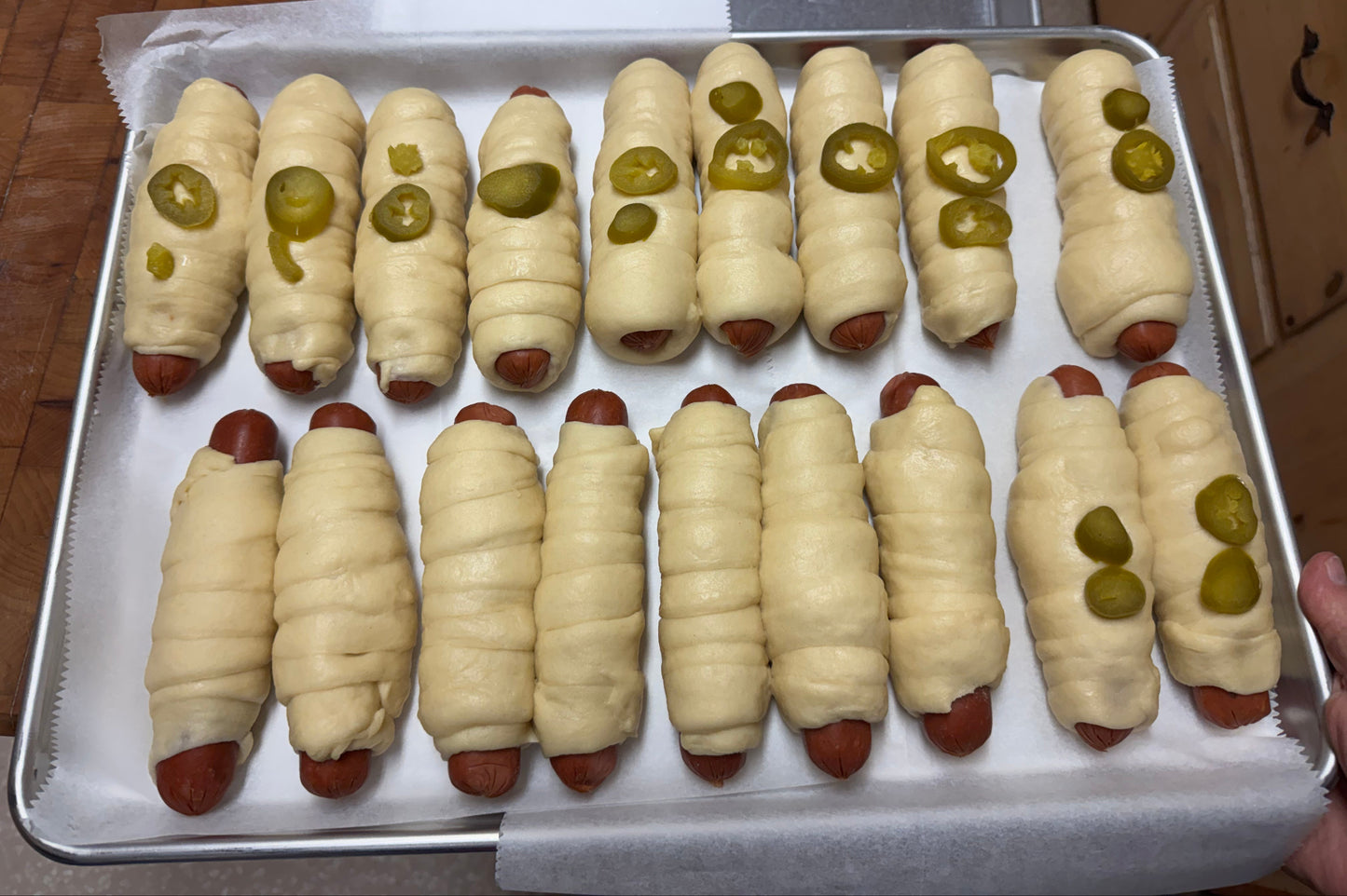 Tray of kolaches with jalapeño slices on a baking sheet ready to go in the oven.