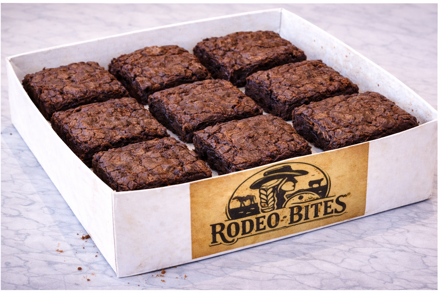 Box of Rodeo Bites brownies in a Rodeo Bites box on a marble surface.