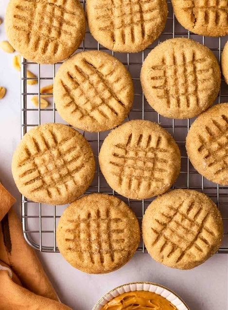 A photo of several peanut butter cookies cooling on a wire rack.
